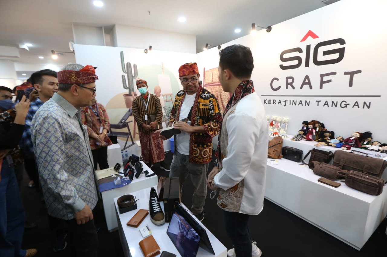 Pemilik Crown Leather (UMKM binaan SIG), M. Adrian Fadhilah (kanan) menunjukkan produk kerajinan tangan dari kulit sapi kepada Staf Khusus III Menteri BUMN, Arya Sinulingga (kiri) pada acara “Bazar UMKM Untuk Indonesia 2023” yang diselenggarakan Kementerian BUMN di Gedung Sarinah, Jakarta, Kamis, 26 Januari 2023. dok. ist.1). SIG Fasilitasi 32 UMKM Binaan Ikuti Bazar UMKM Untuk Indonesia 2023