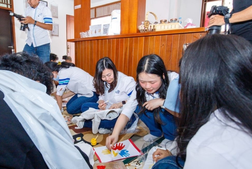 Finance Director Asuransi Astra, Herlin Agustina, mendampingi anak-anak Yayasan Teman Hebat Berkarya dalam kegiatan melukis di atas kaus, salah satu rangkaian aktivitas employee volunteering yang dirancang karyawan Asuransi Astra. Asuransi Astra Peringati 69 Tahun di Sekolah Penyandang Disabilitas